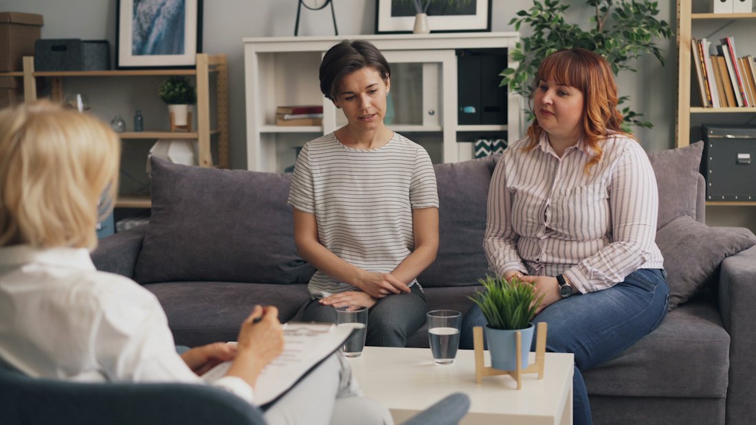 Two women on a couch, talking
