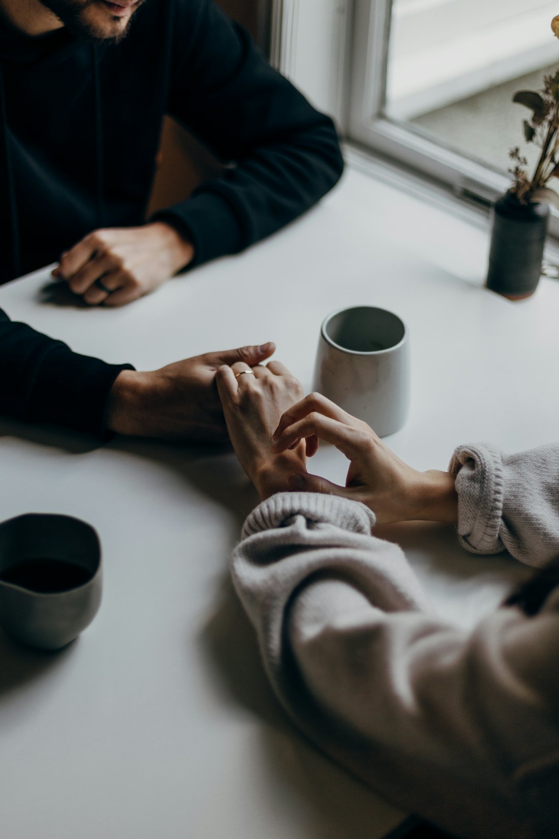 Two people holding hands across a table